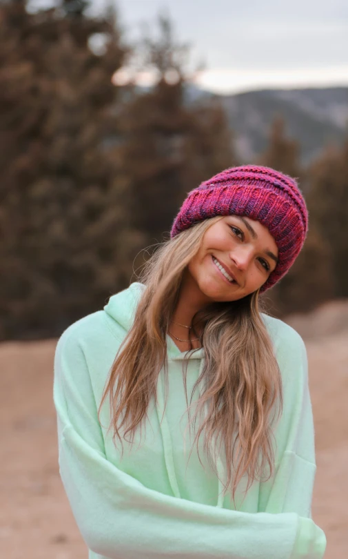 a woman wearing a pink beanie smiles for the camera