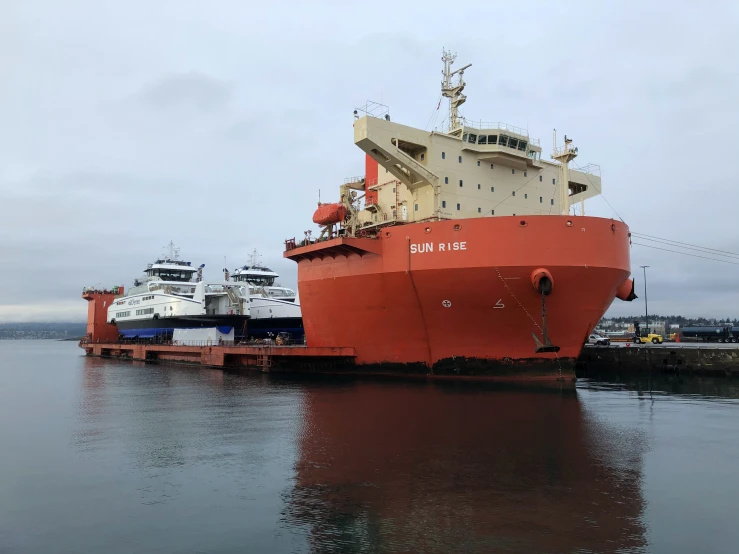 an orange ship sitting next to another boat