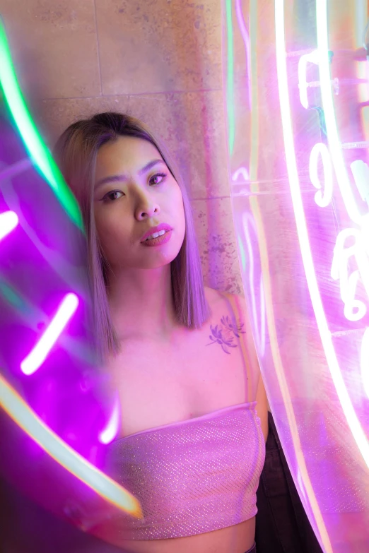 a woman poses in front of neon lights