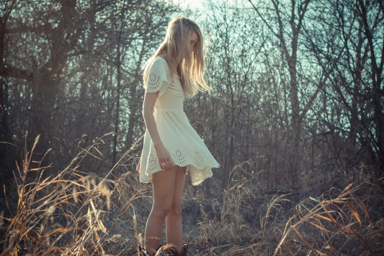 a woman standing in the woods wearing a white dress