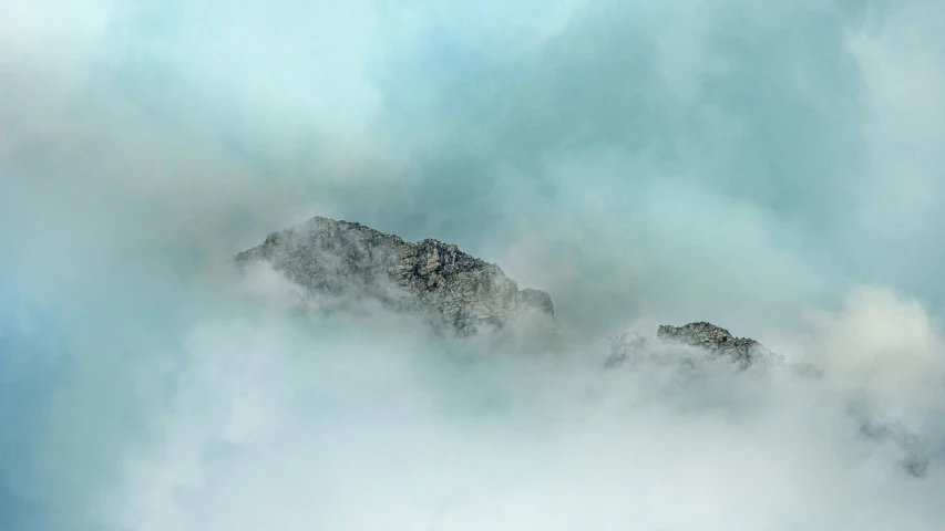 a mountain covered in cloud under a blue sky