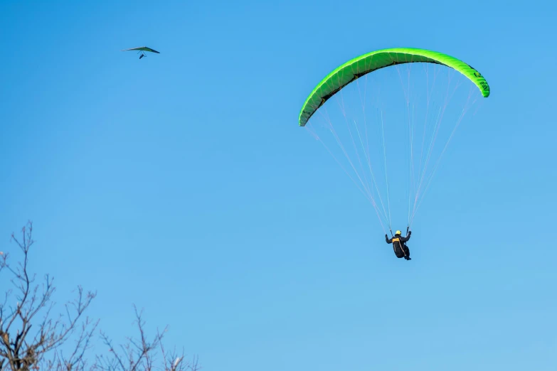 man para sailing in the blue sky with two large parachutes