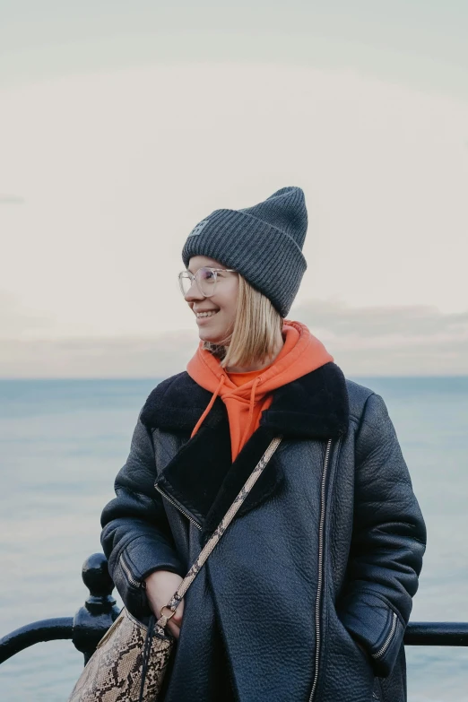 a woman is smiling while standing near the ocean