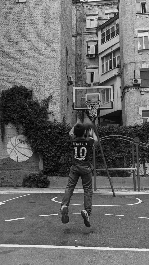 a young person playing basketball in a parking lot