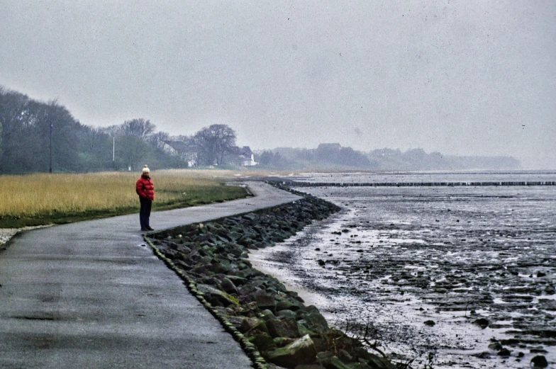 a man walking down a pathway next to a beach