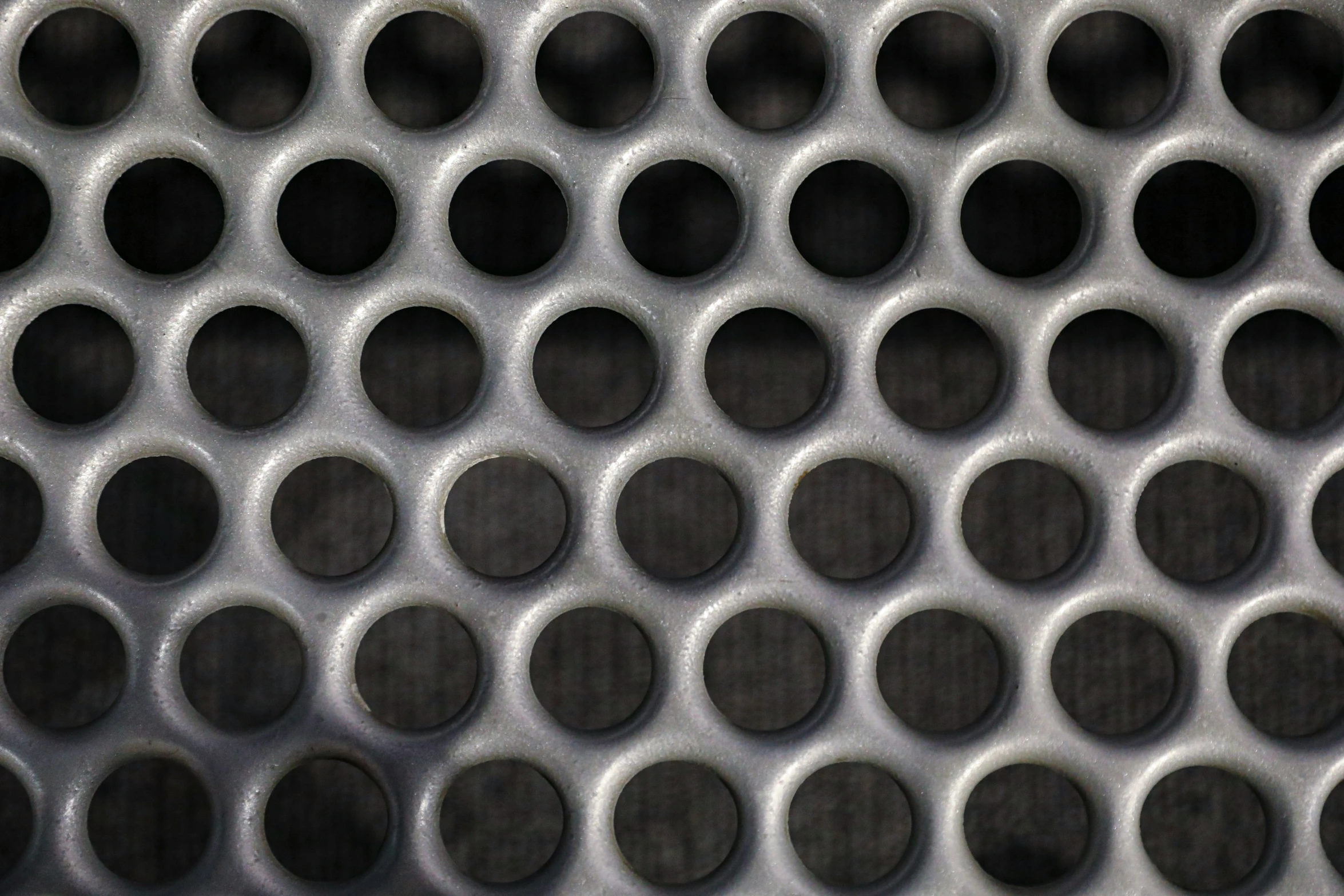 a large metallic grate has circles of black dots on it