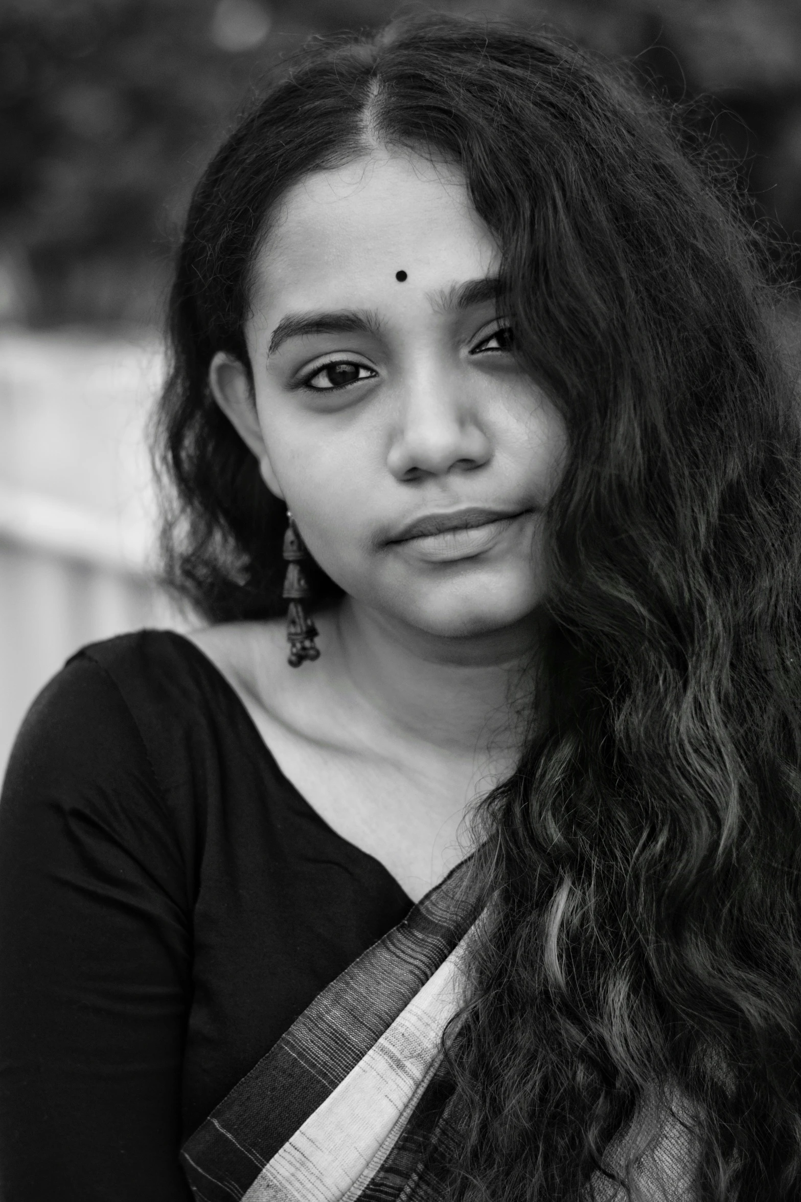 a young indian woman with long hair and earrings