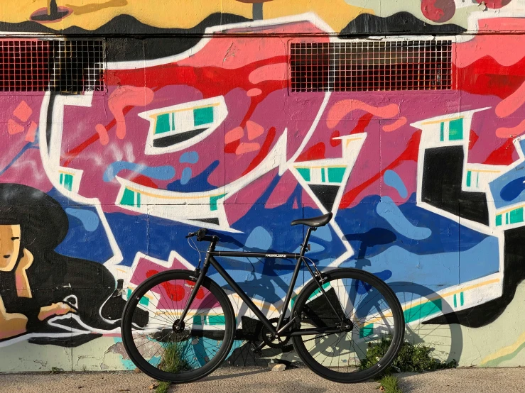 a bicycle parked in front of a colorful graffiti wall