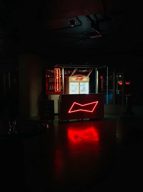 a red neon sign and bar in a dark room