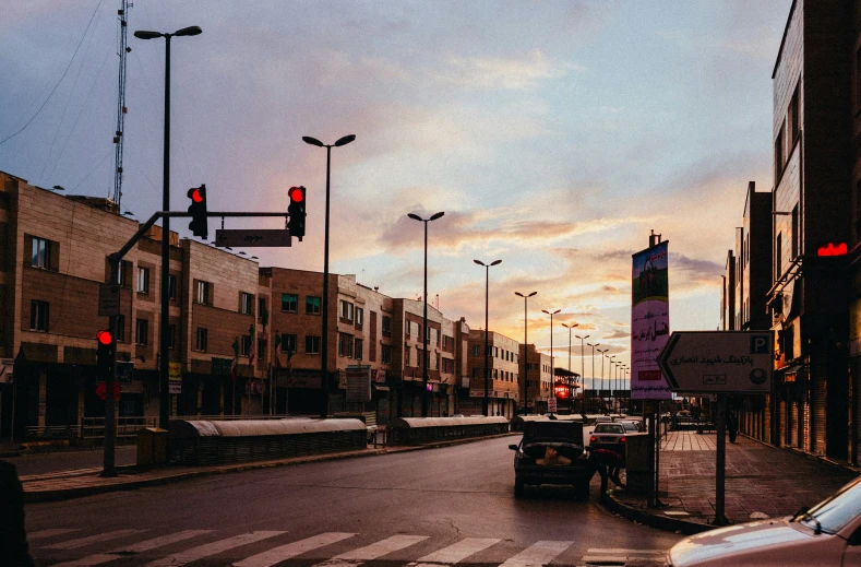 city street lights on and cars parked on the side of the road