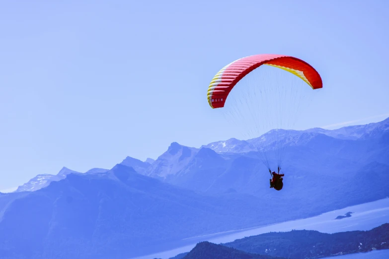 a man who is on the side of the mountain para sailing