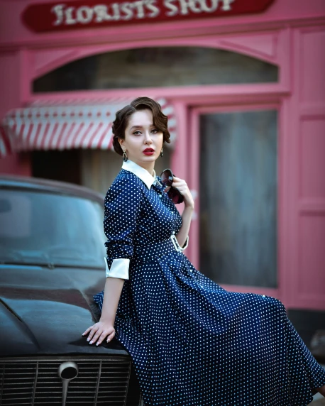 a woman in blue dress sitting on top of a car