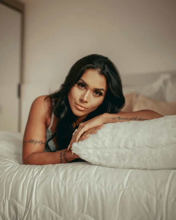 a woman sitting on top of a white bed with white sheets