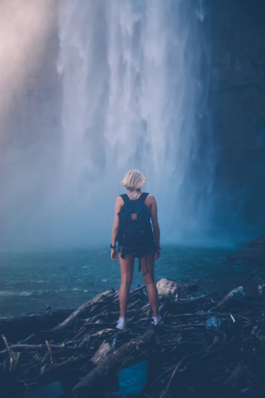 a person with backpack standing near waterfall