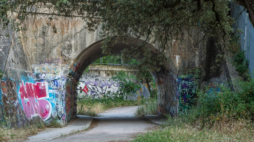 an old tunnel covered in graffiti next to grass
