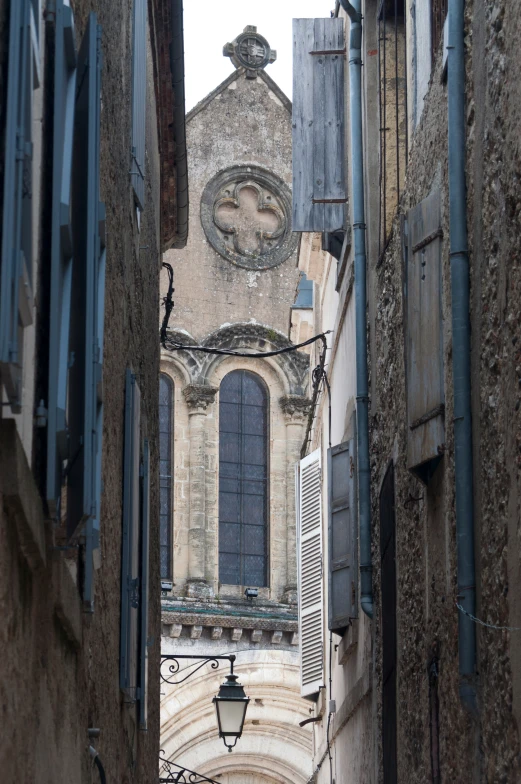 a narrow alley with an old clock tower in the background