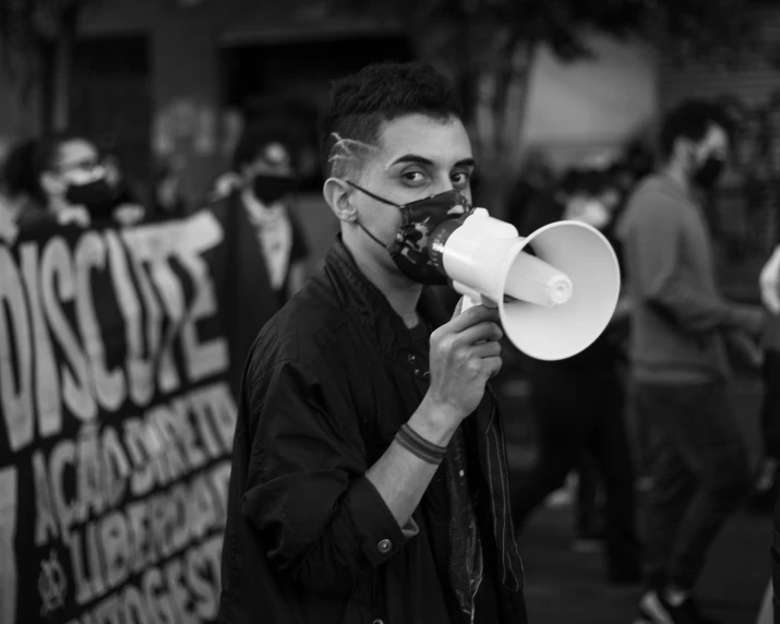 a man speaking into a white bullhorn megaphone while standing