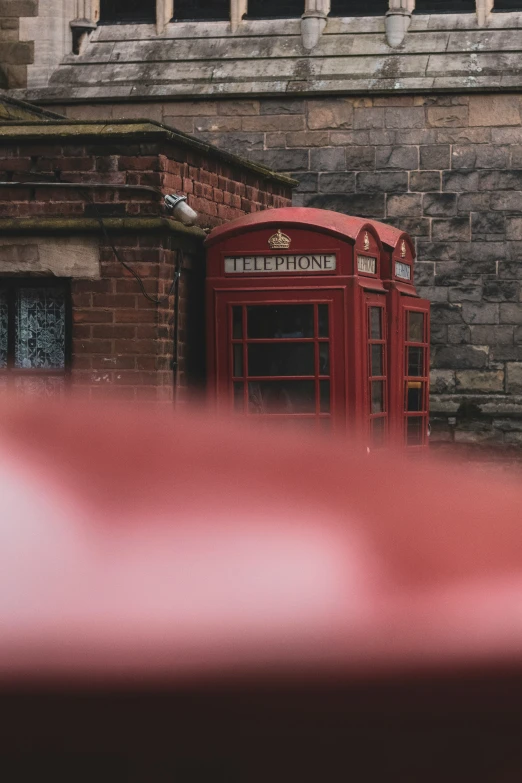 a red phone booth next to a tall brick building