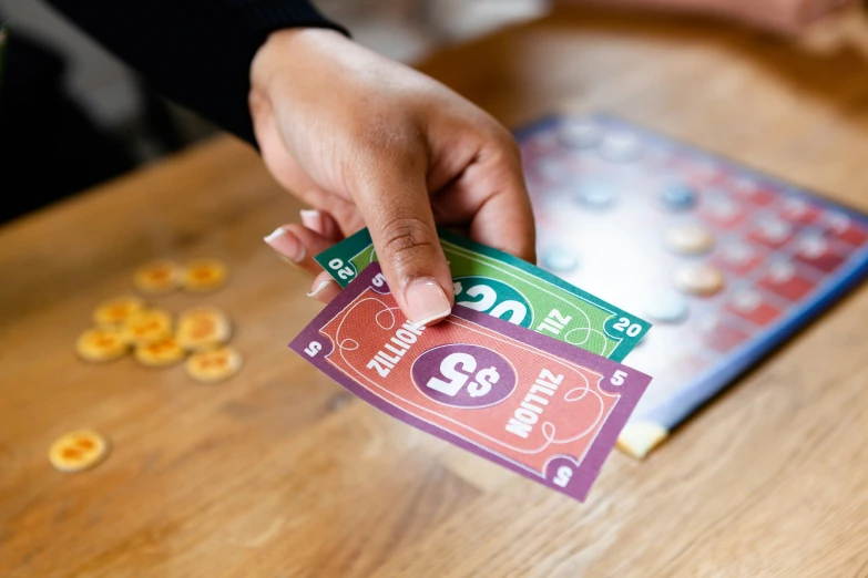 hand on a playing monopoly card on table