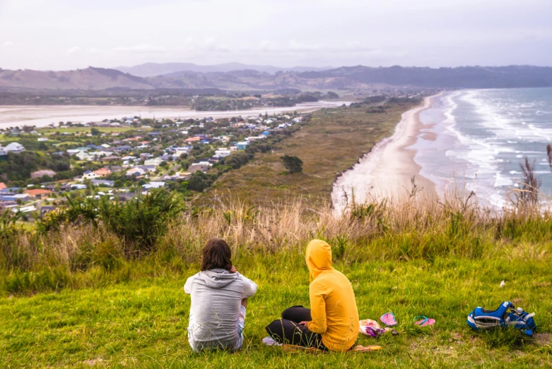 two people sit on the side of a hill