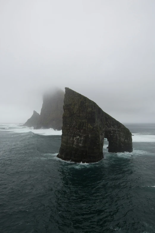 an old rock sticking out from the ocean