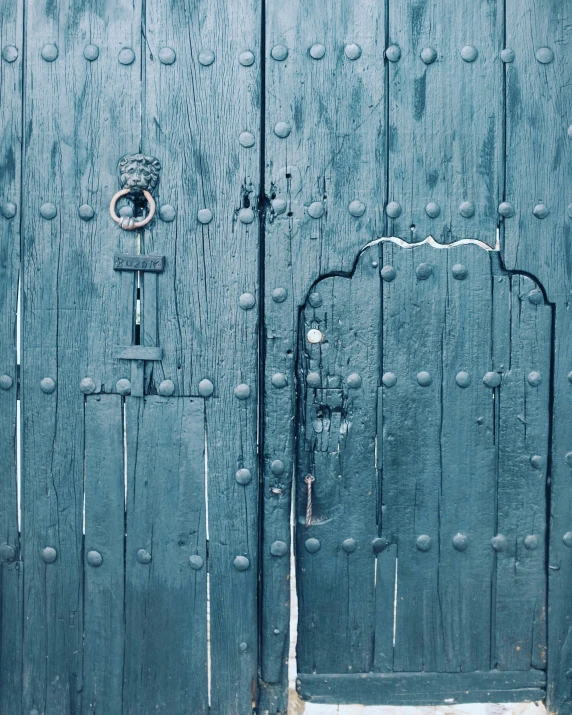 two green doors and an ornamental handle with rivets