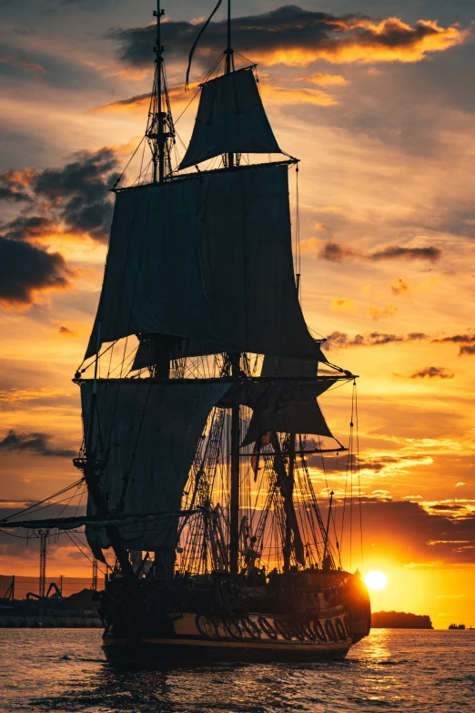 the sun sets behind the tall ships sailing in the water