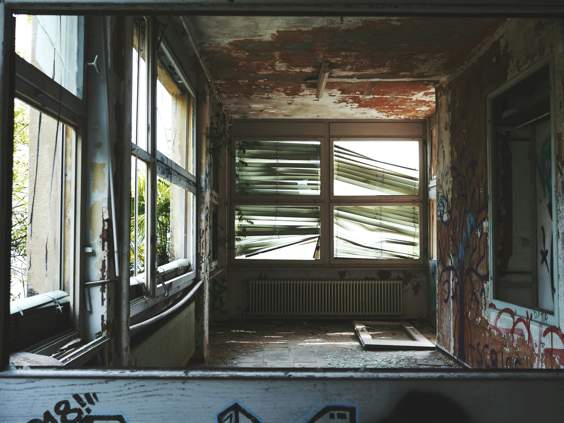 an open window in a rundown house next to some graffiti