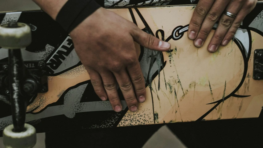 two people hold their hands over the side of a skate board
