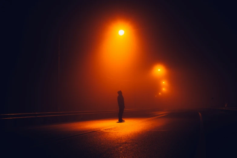 a person standing on the side of a road at night