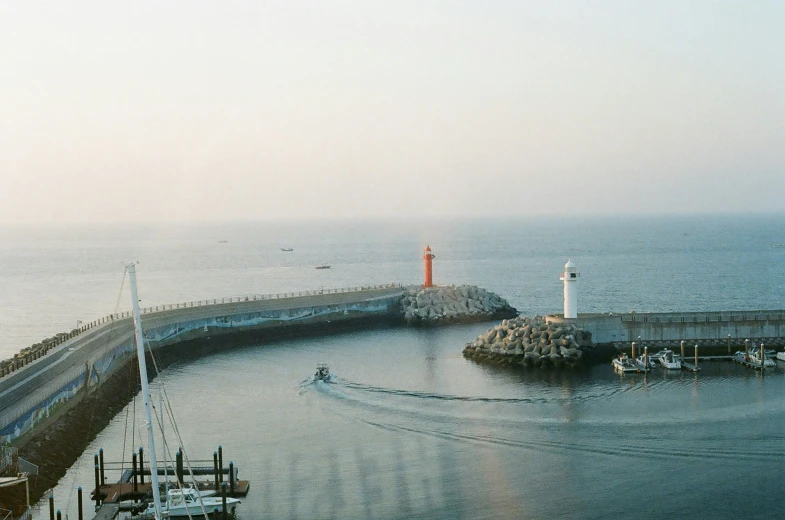 a pier with boats near a lighthouse on a bright day