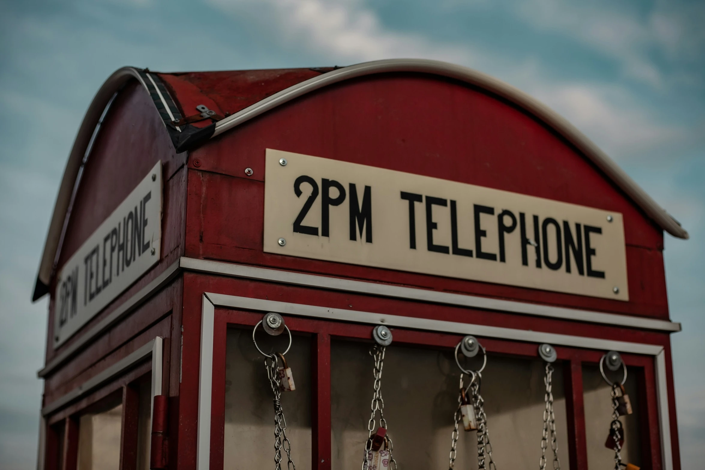 a red telephone booth with metal chains hanging on the front