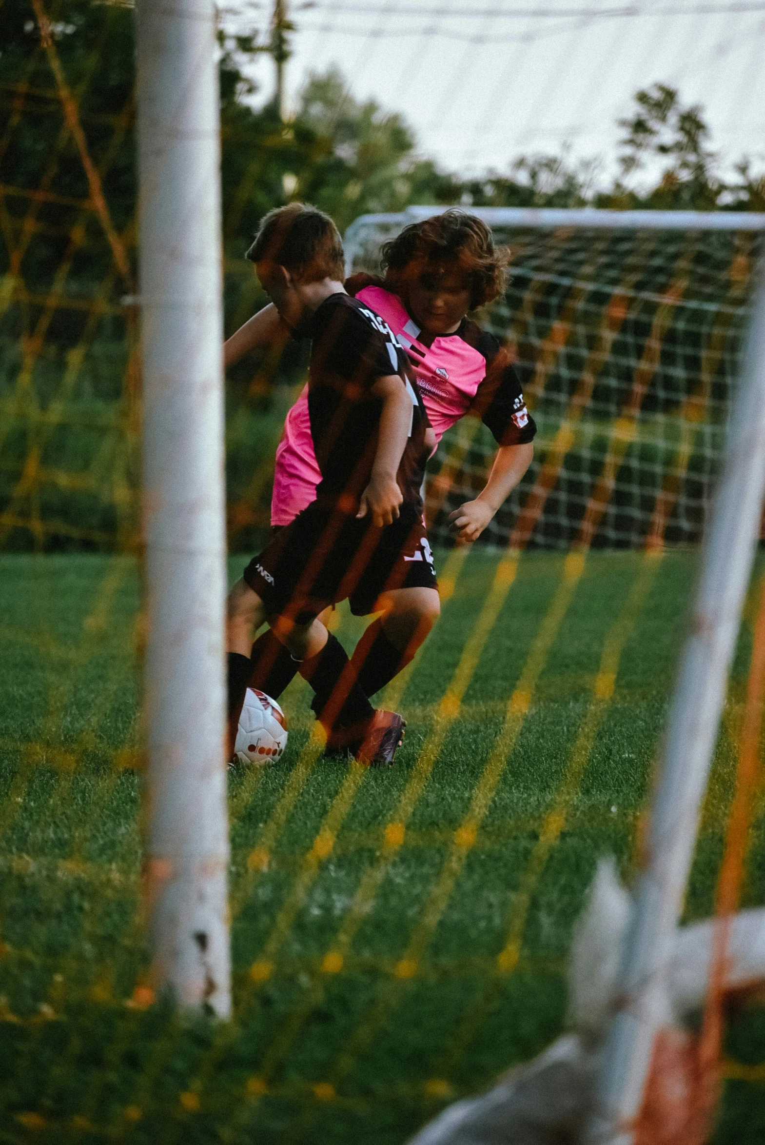 two young men playing soccer next to a goal