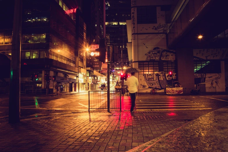 a person crossing the street at night with their umbrella open