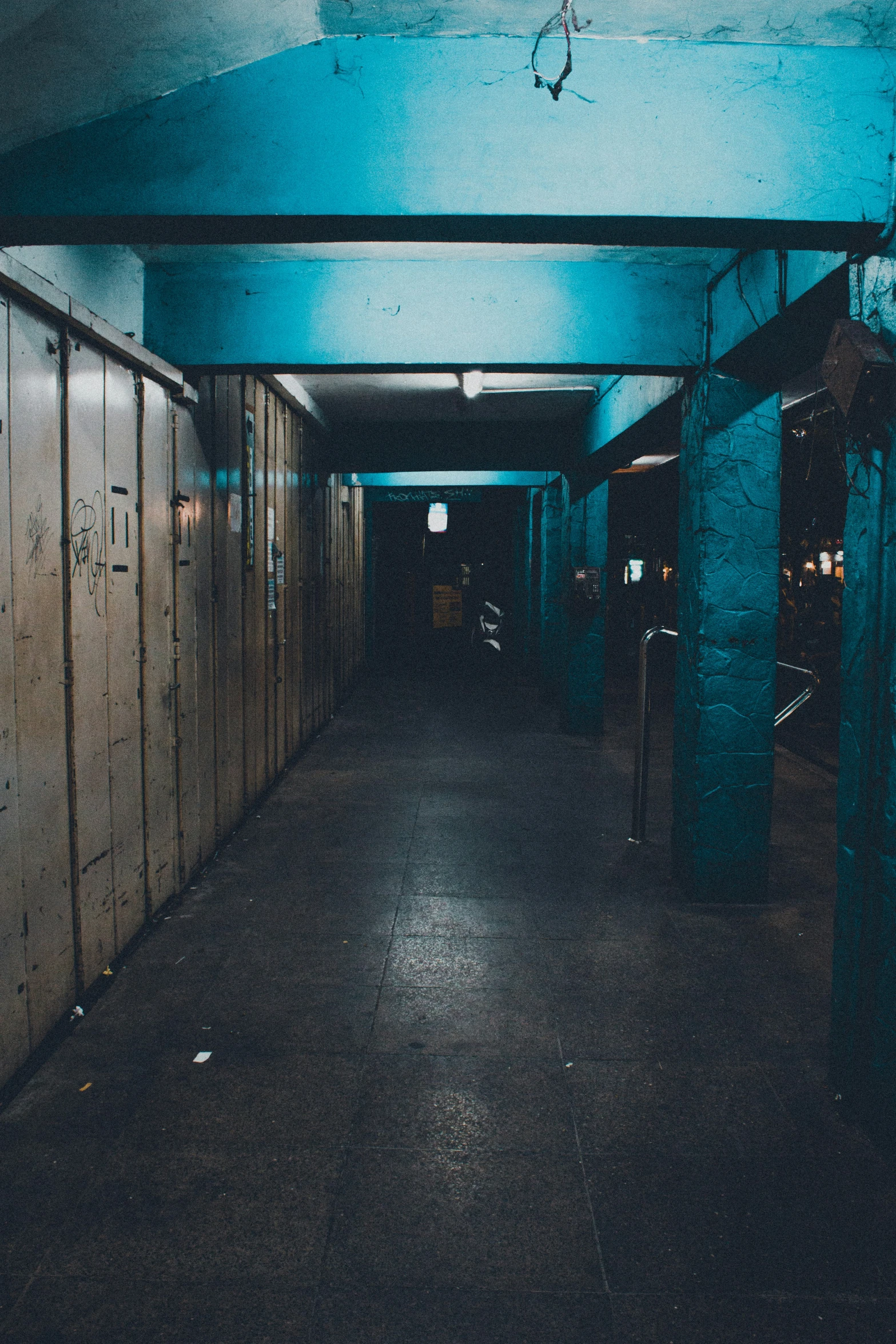 an empty corridor is dimly lit by blue lighting