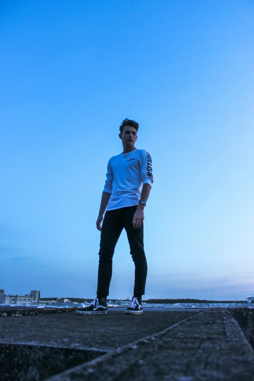 a man is standing by the water on his skateboard