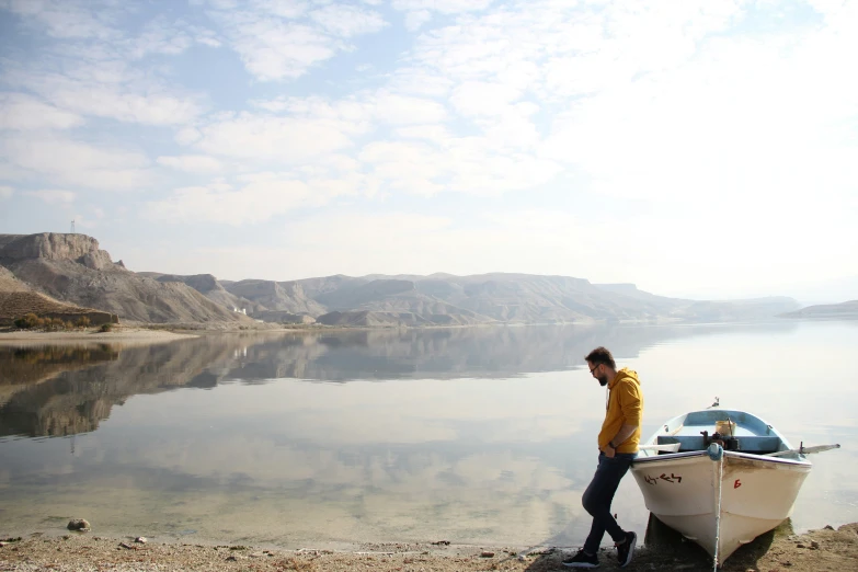 man standing on the bank of the river beside a boat