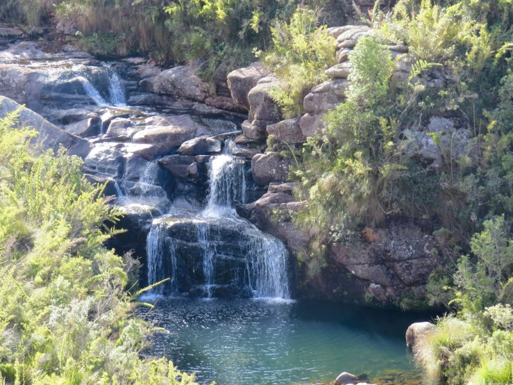 a waterfall is next to some rocks and trees