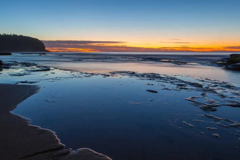 the sunset with water on the sand, some of it shining