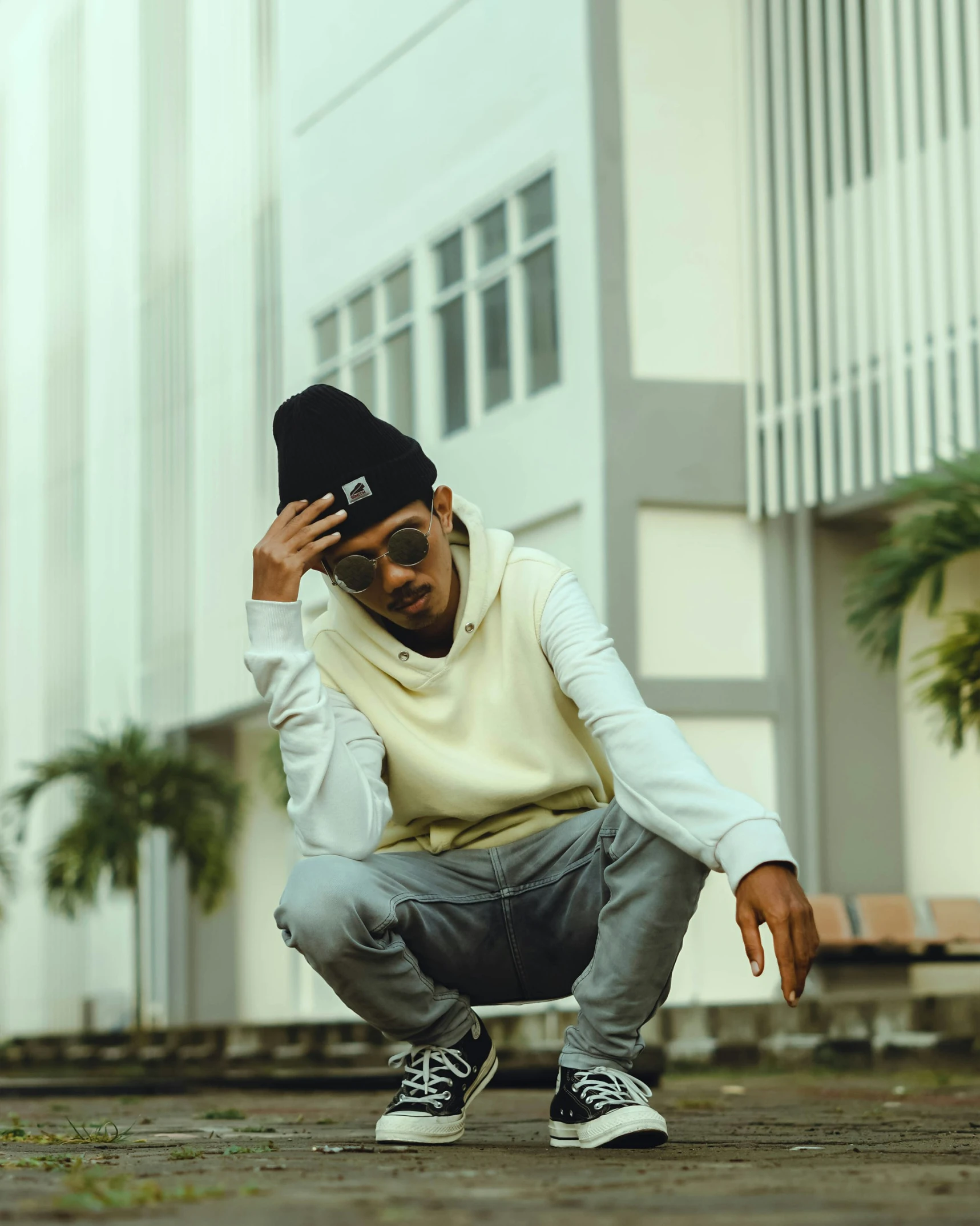 a man crouching down and adjusting his hat