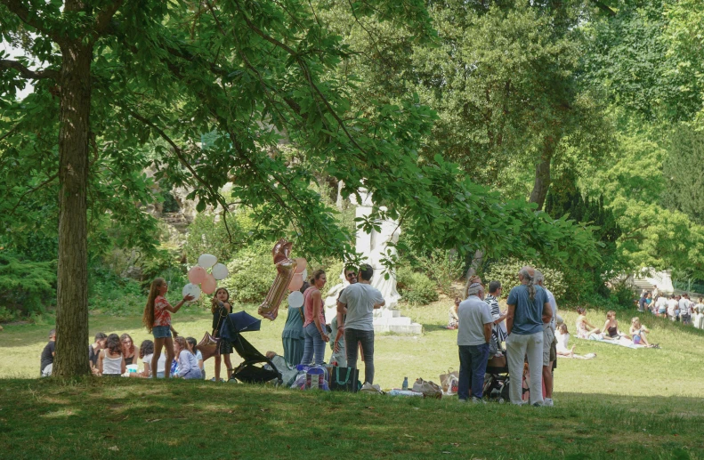 several people gathered around in a park on the grass