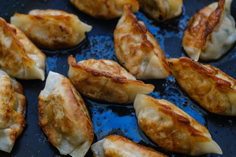 many fried dumplings are sitting on a black pan