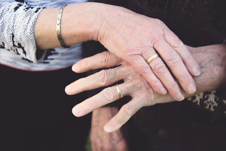 a close up of an old lady holding on to her wedding rings
