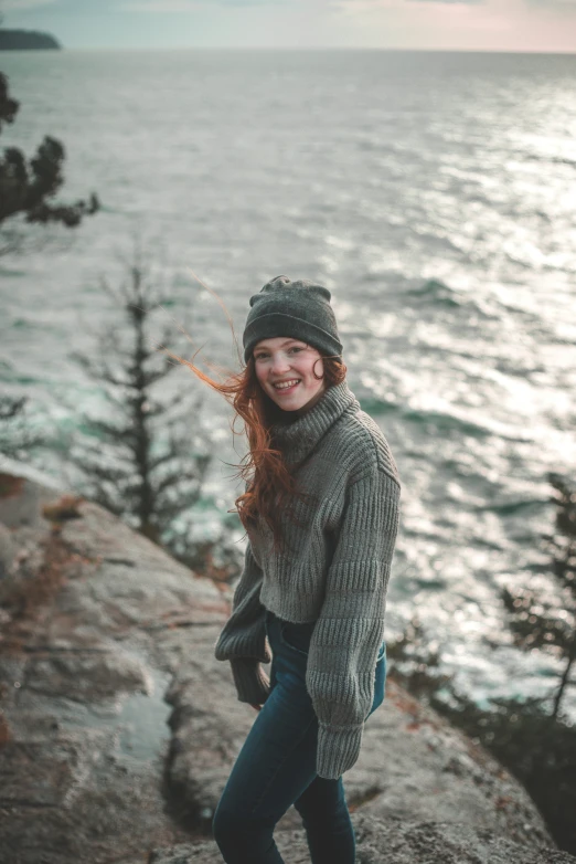 a girl smiles near the water in her wooly winter gear