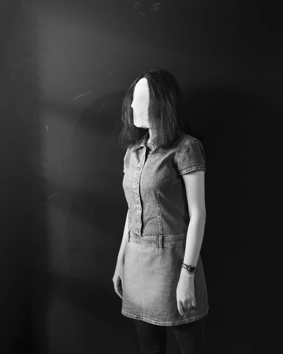 a woman stands against a wall wearing a dress