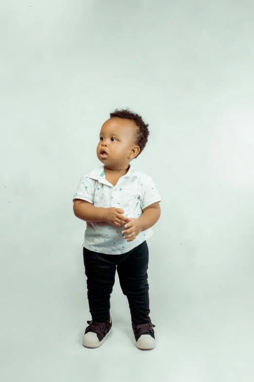 baby standing up against a white background posing for a portrait