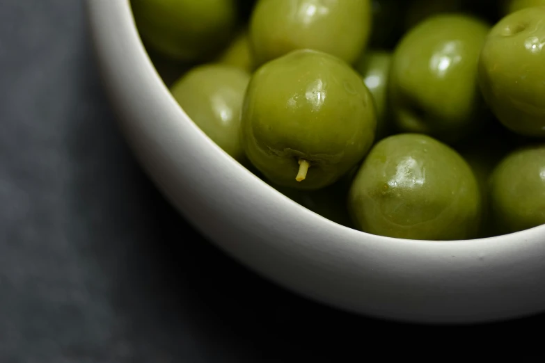 green fruits in a white bowl on a table