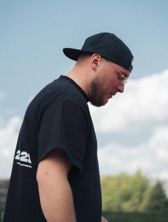 man wearing black t - shirt and hat in open field