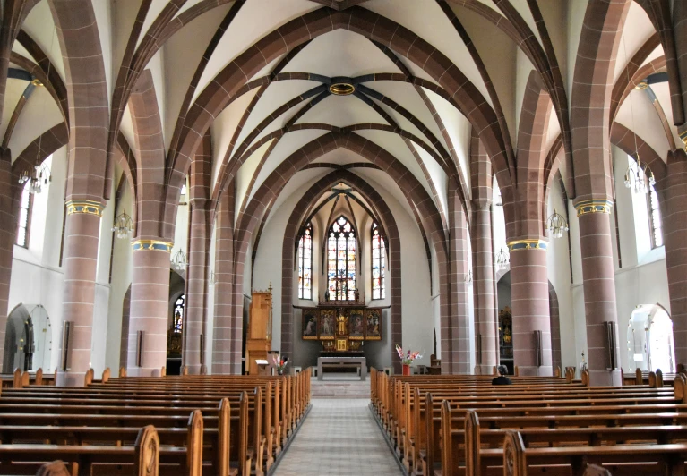 a cathedral with large windows, high vaulted ceiling and wooden pews