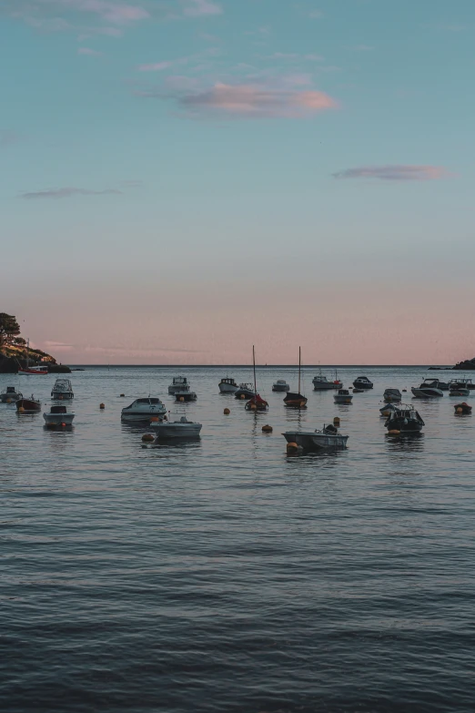 several boats floating on the water at dusk